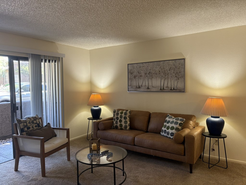 A living room with a brown couch, a chair, a coffee table, and two lamps.
