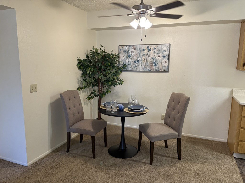 A dining room with a table, chairs and a ceiling fan.
