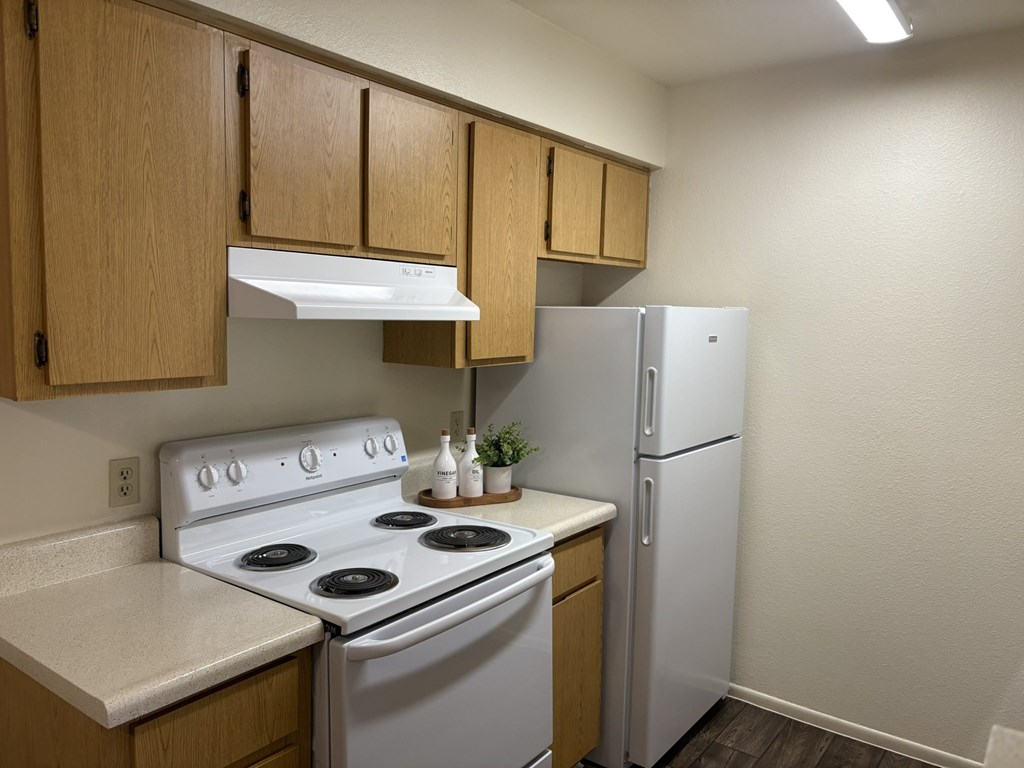 A kitchen with a white stove and a white refrigerator.
