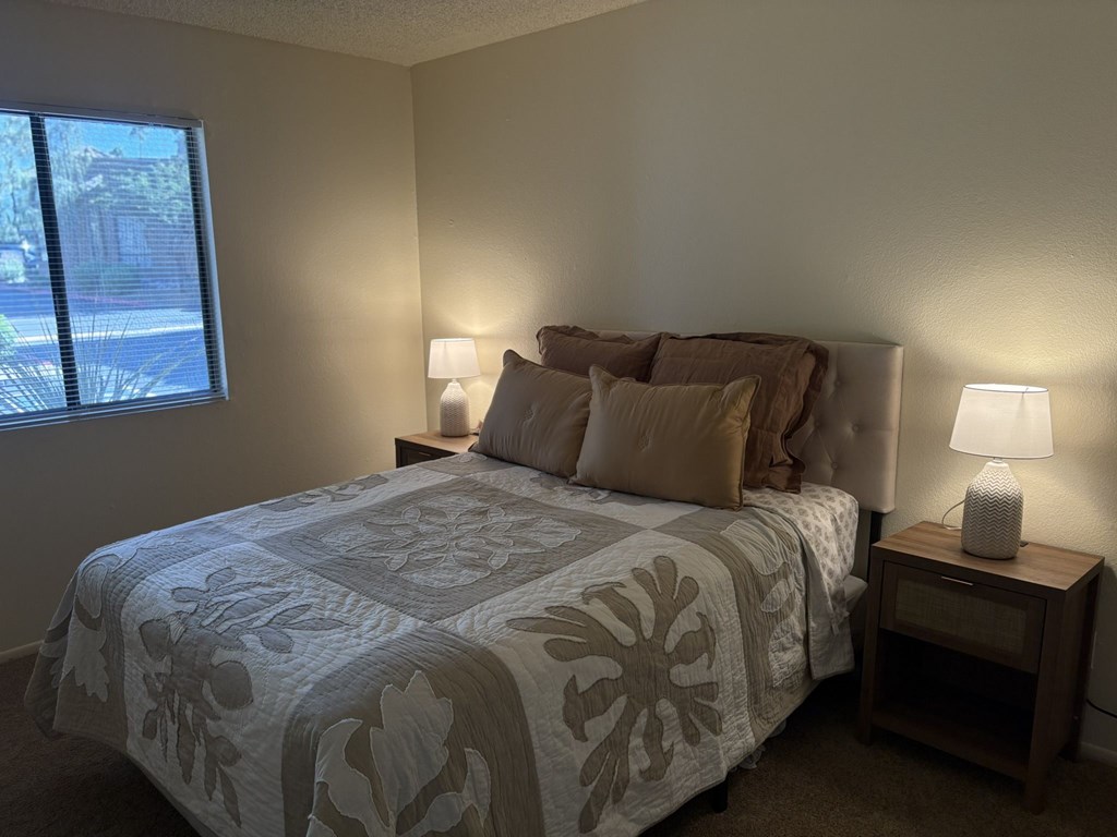 A bedroom with a bed, nightstand, and two lamps.