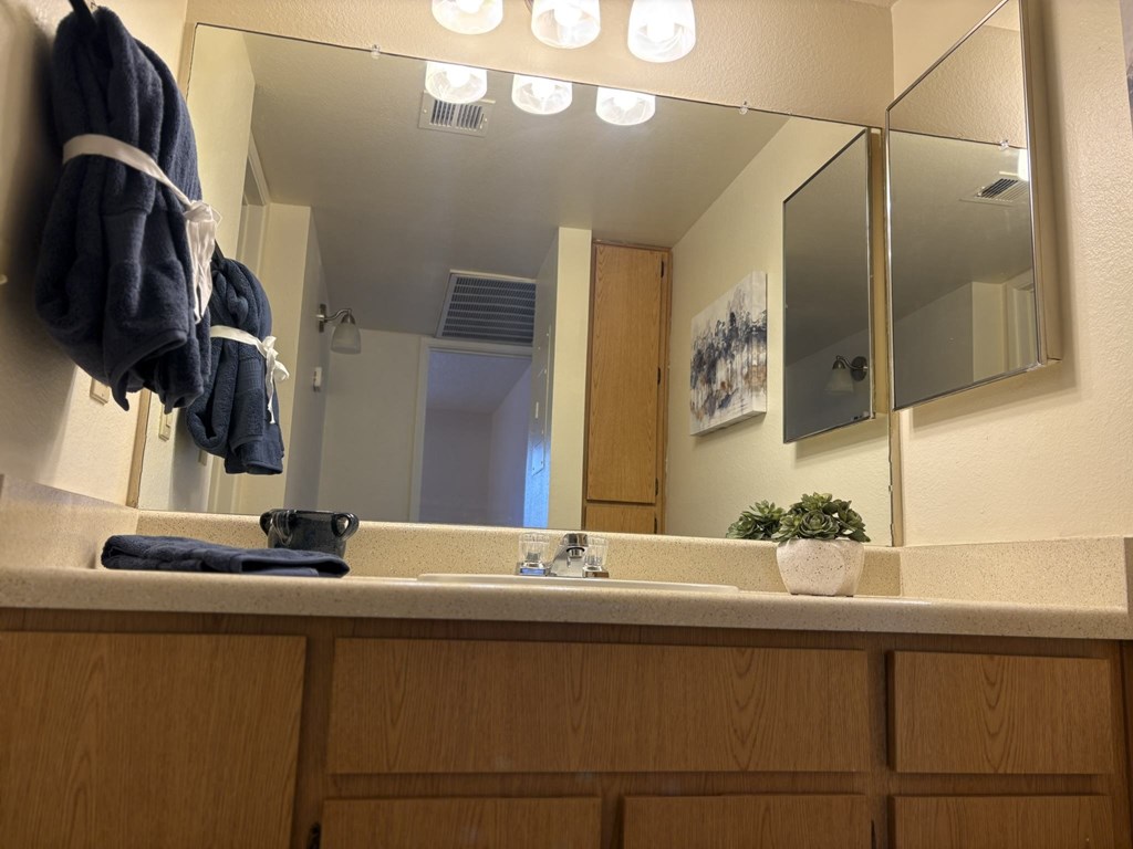 A bathroom with a mirror, sink, and towel rack.