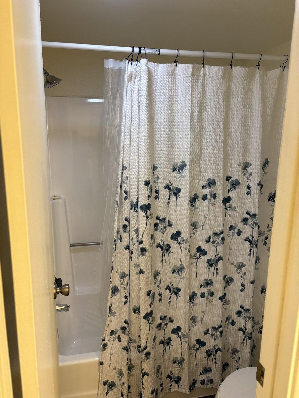 A shower curtain with a floral pattern hangs in a bathroom.