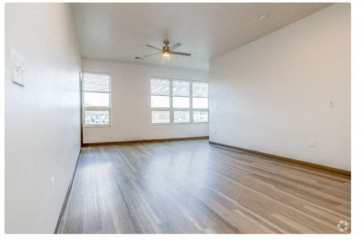 an empty living room with white walls and a ceiling fan