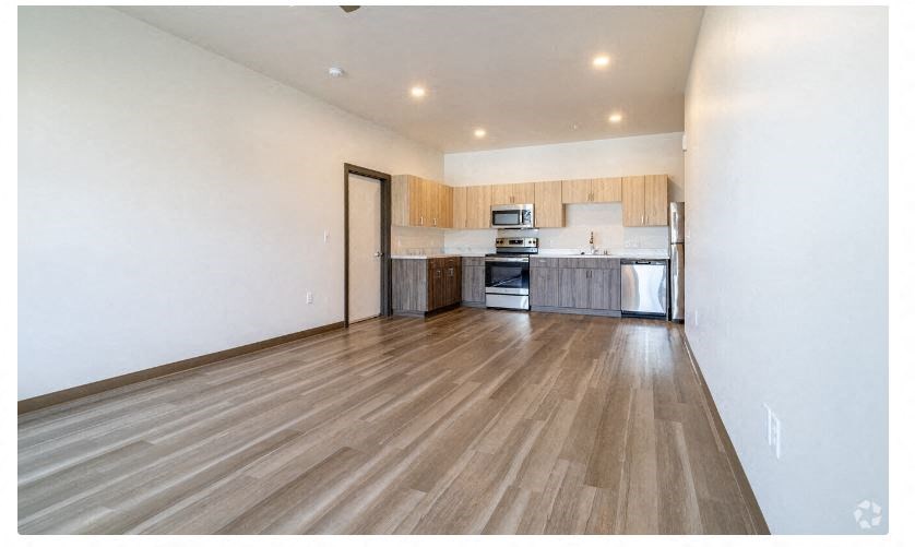 an empty living room and kitchen with wood floors