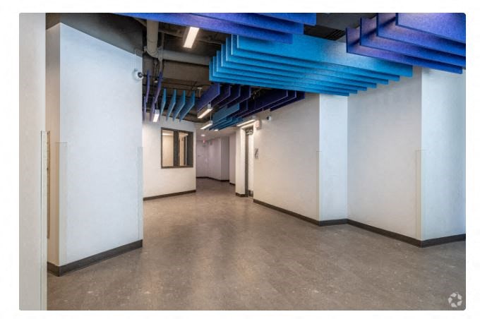 an empty room with white walls and blue pipes on the ceiling