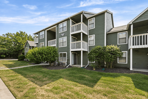 Apartment complex with green buildings and a clear sky.