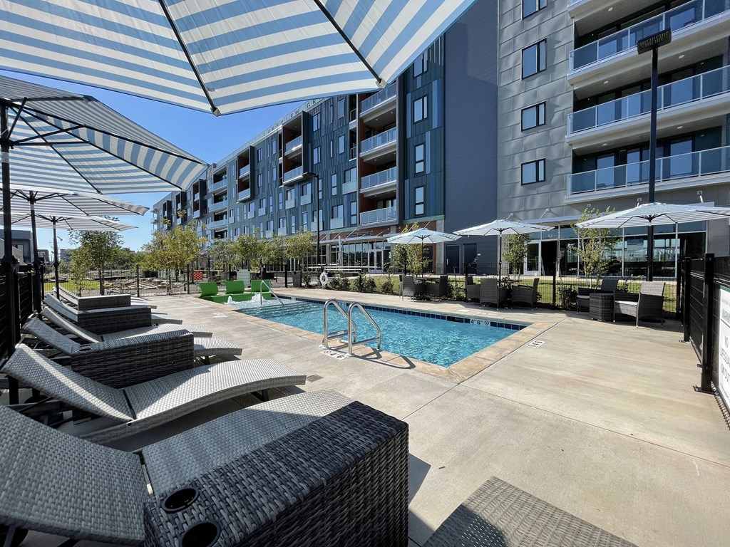 a pool with lounge chairs and umbrellas in front of a building