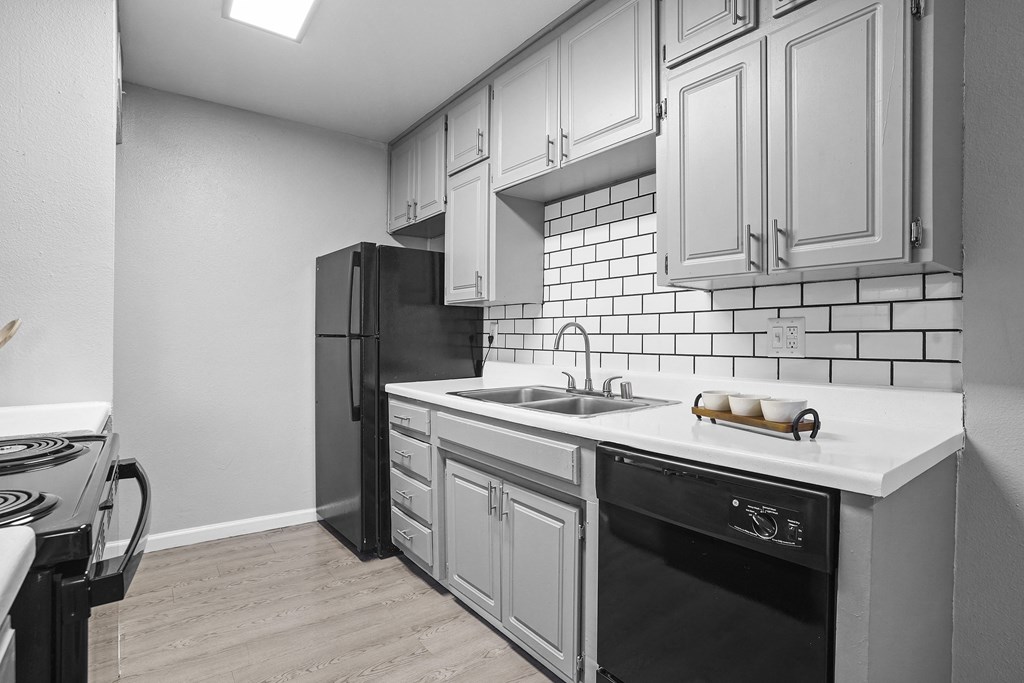 an empty kitchen with white cabinets and a black refrigerator