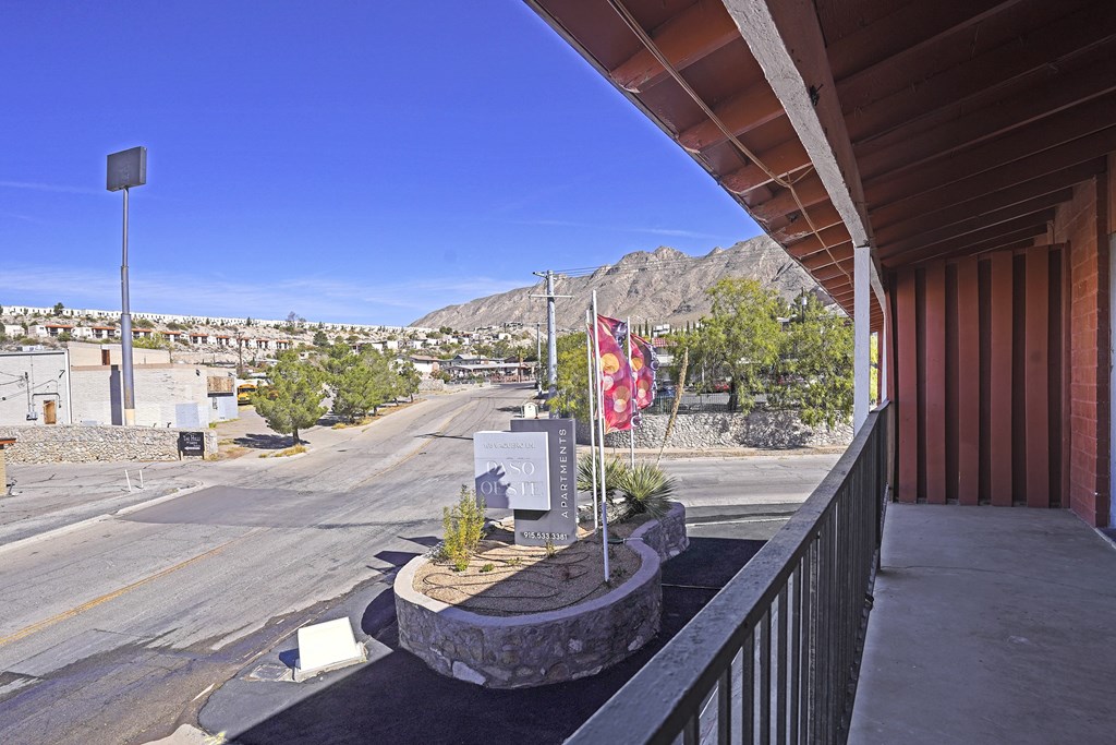 the view from the front porch of a building overlooking a city street and a flag