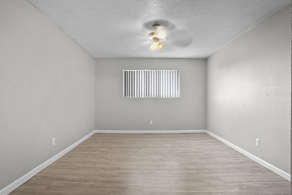 an empty room with a ceiling fan and a window