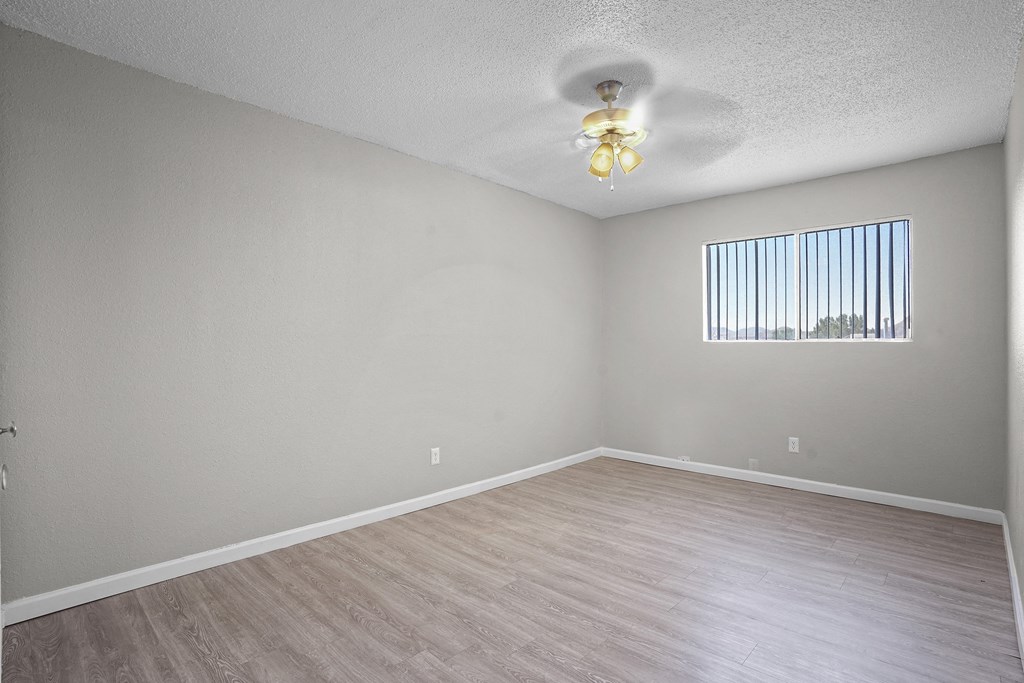 the spacious living room with wood flooring and a ceiling fan