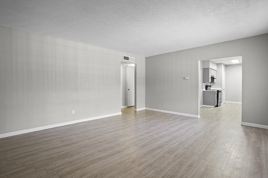 an empty living room with wood flooring and white walls