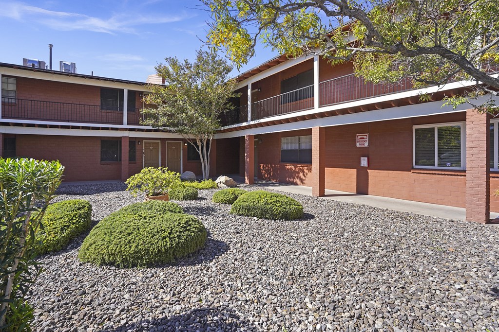 a courtyard with gravel and bushes in front of a building