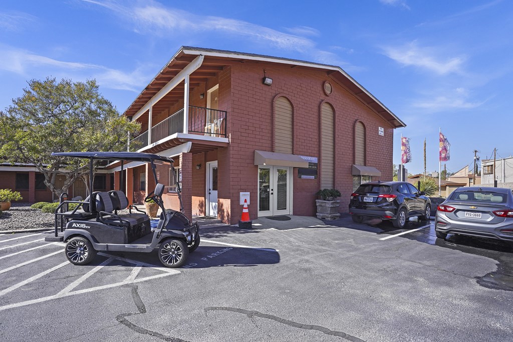 a parking lot in front of a brick building with cars parked outside