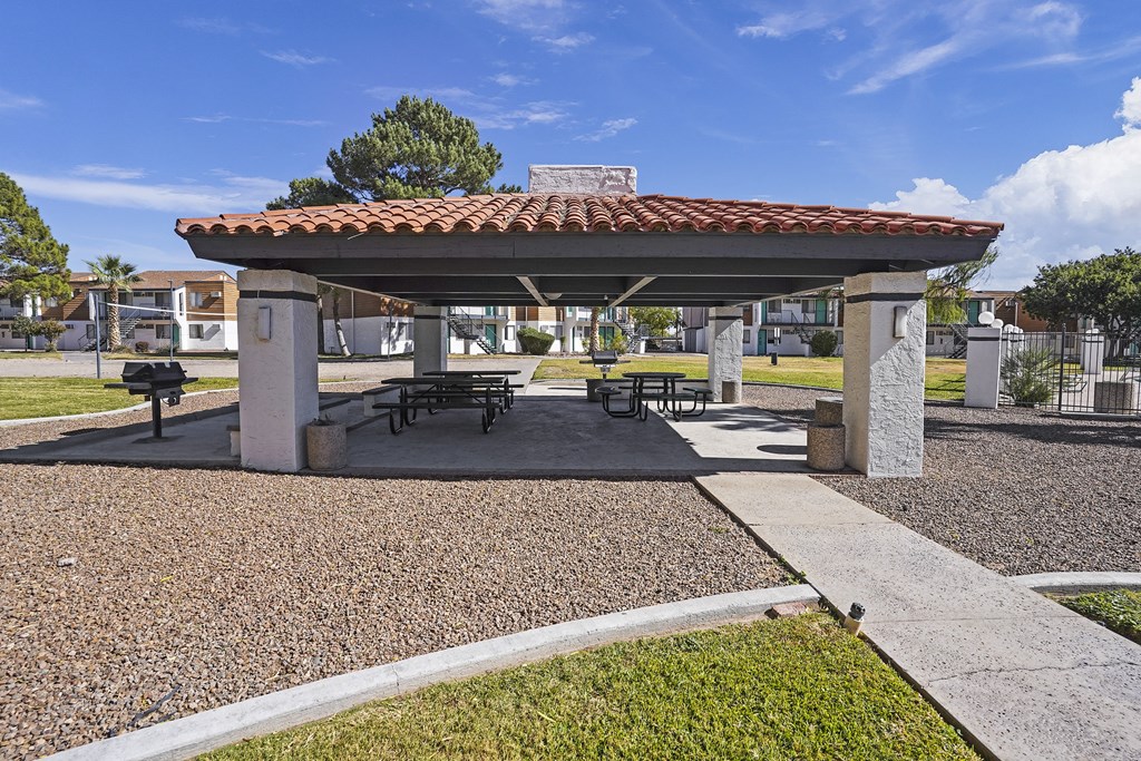 a pavilion with picnic tables and a grill in a park
