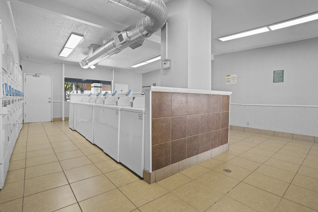 the laundry room of a building with a row of washing machines