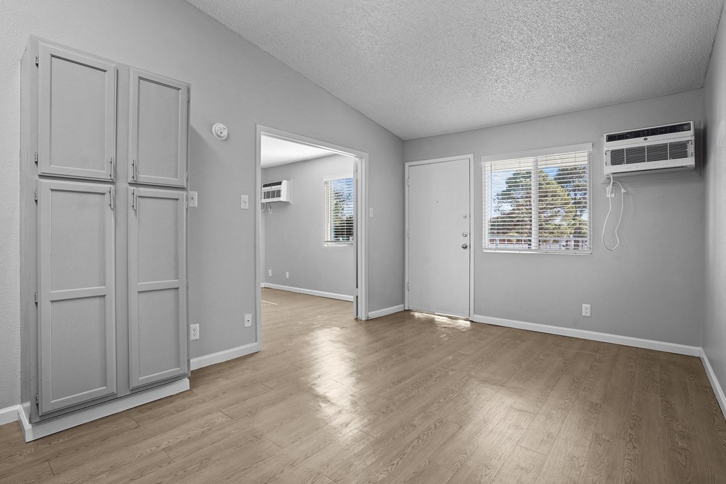 the living room and dining room of an empty house with wood floors and grey walls