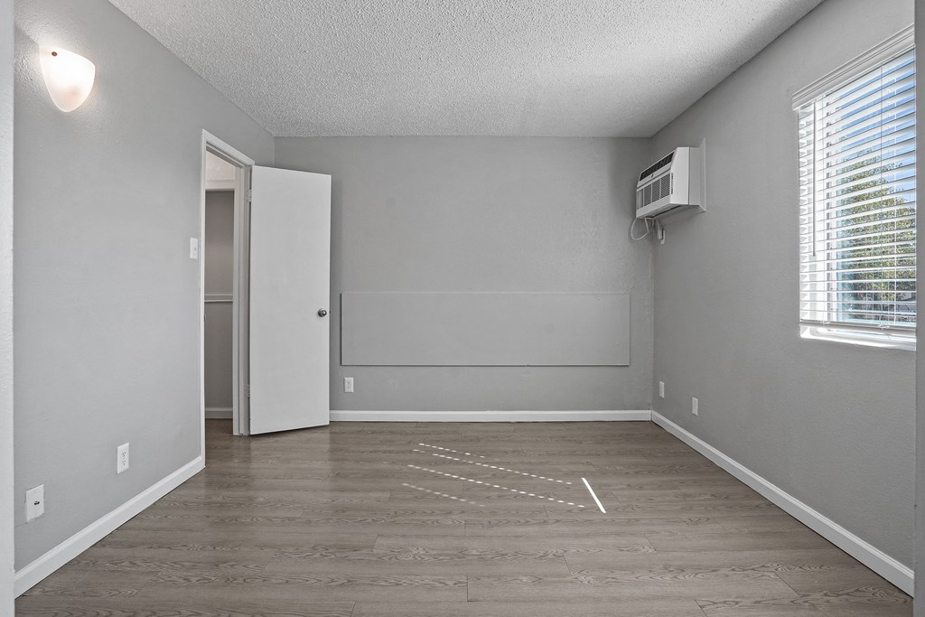 an empty living room with a window and a air conditioner