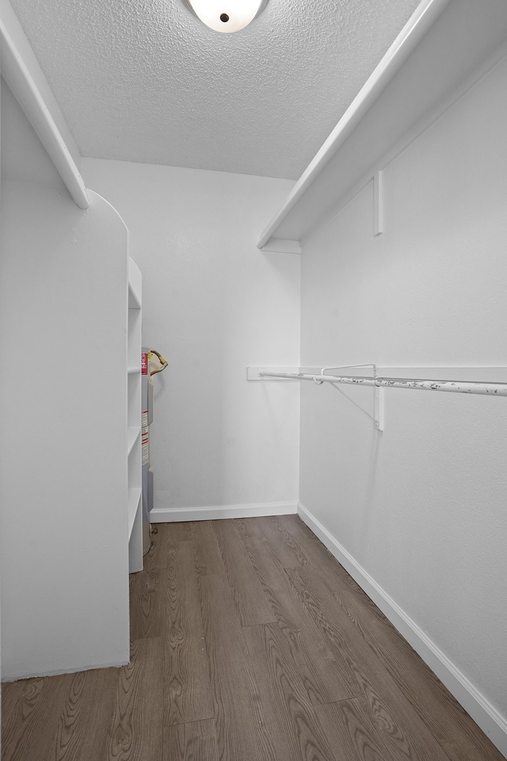 an empty room with white walls and wood flooring and a closet