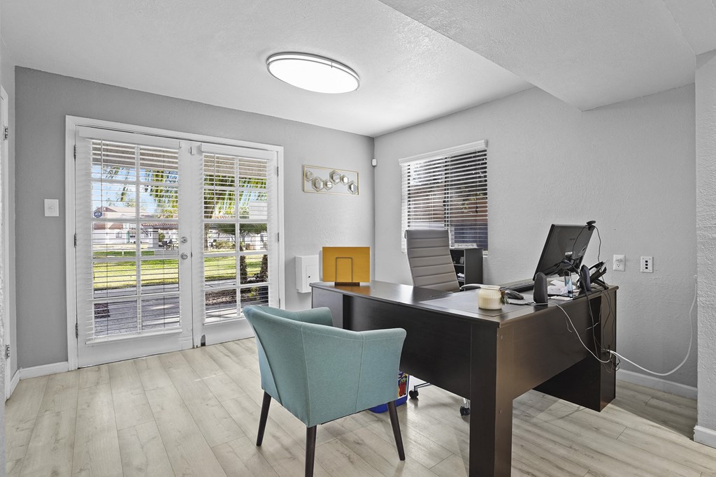 the living room has a desk with two computers and a chair
