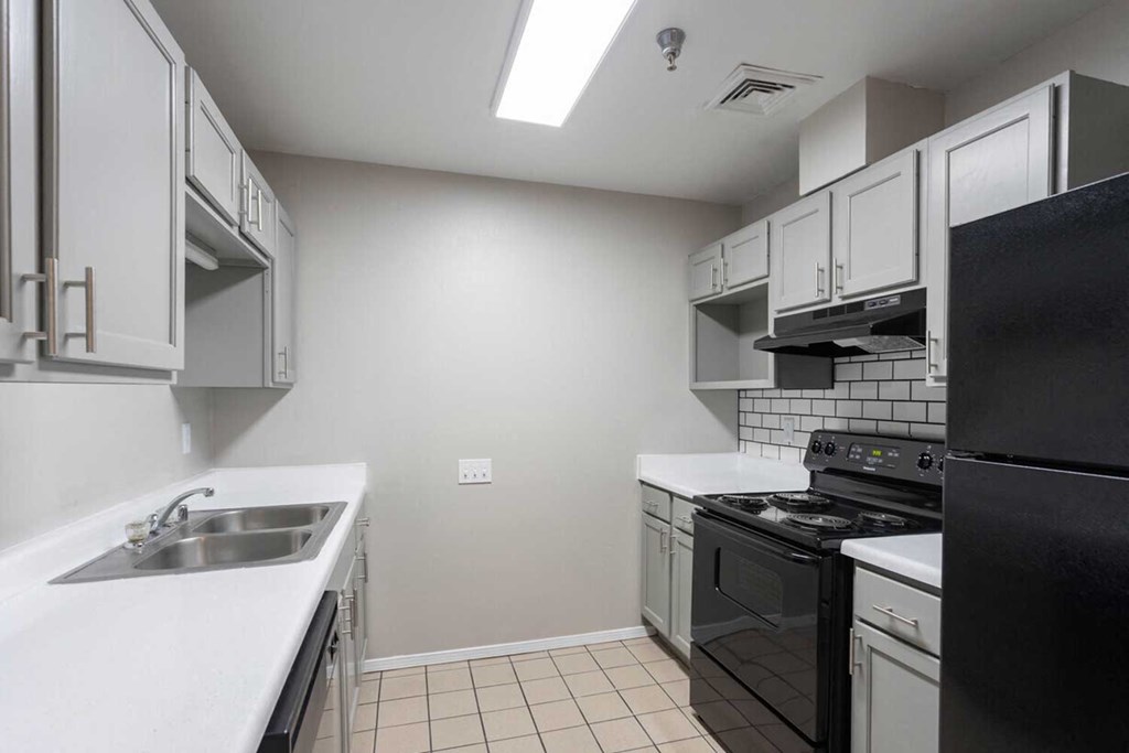 a kitchen with white counter tops and black appliances