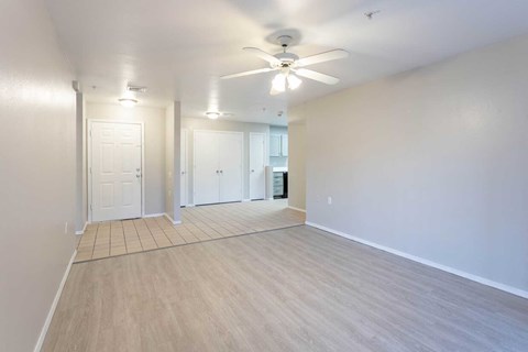 an empty living room with a ceiling fan