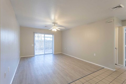 an empty living room with a ceiling fan
