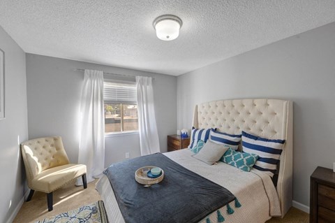 a bedroom with a bed and a chair and a window