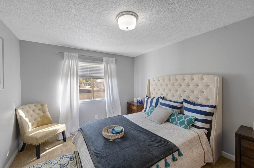a bedroom with a bed and a chair and a window