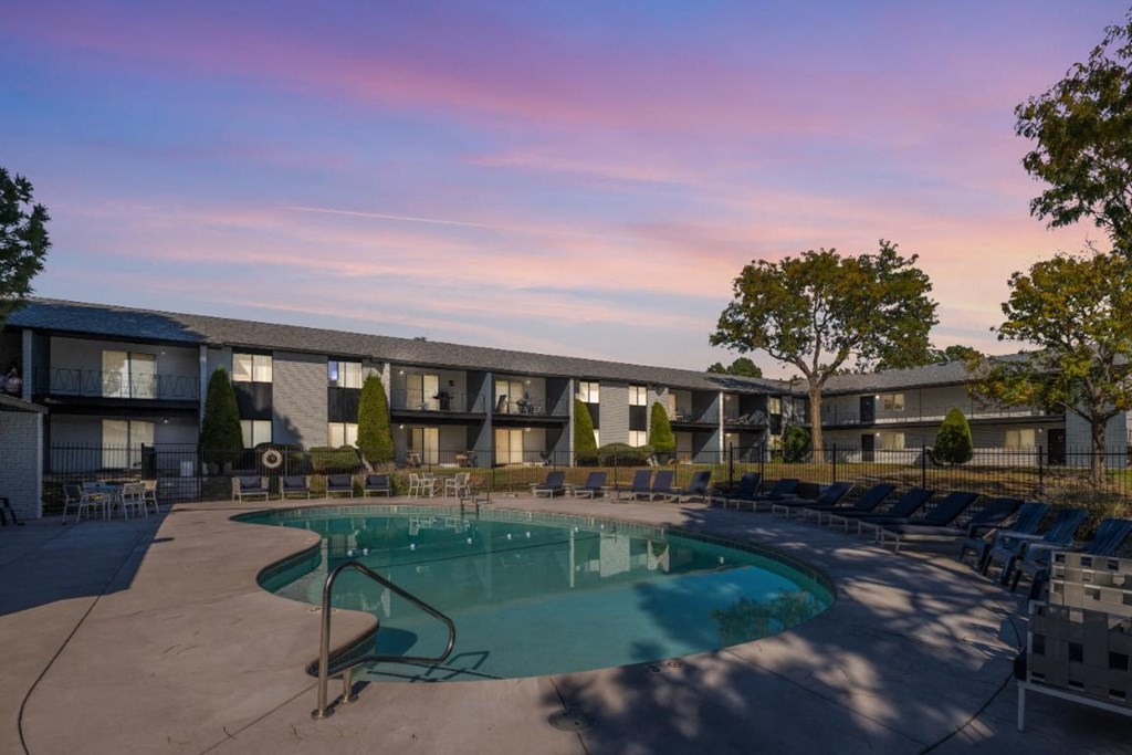 a resort style pool with chairs around it at dusk