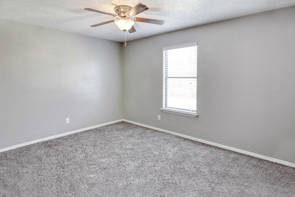 an empty room with a ceiling fan and a window