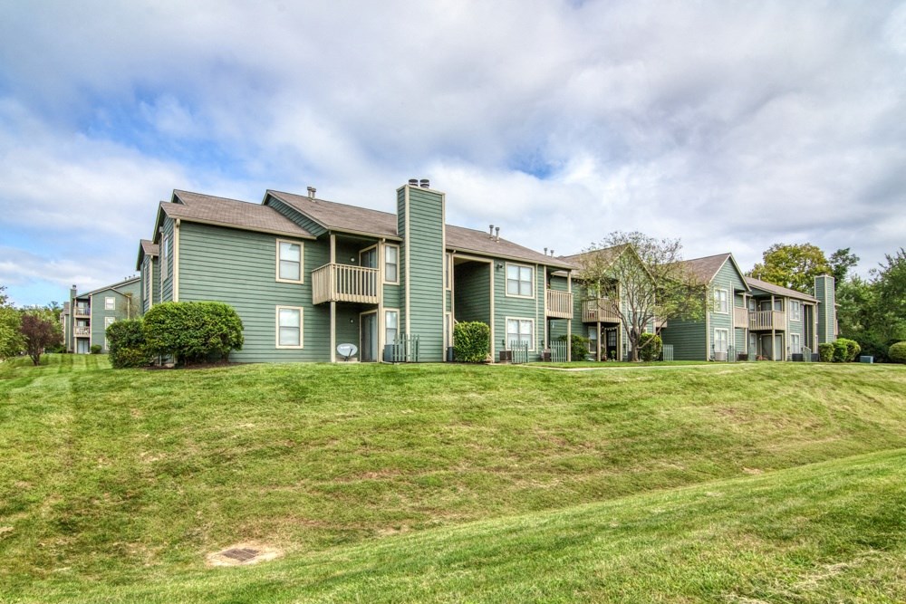 a row of green apartment buildings on top of a grass covered hill