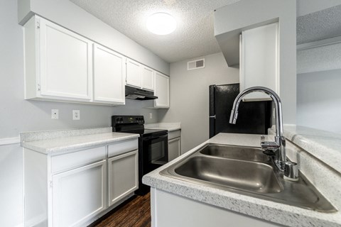 an empty kitchen with white cabinets and a stainless steel sink