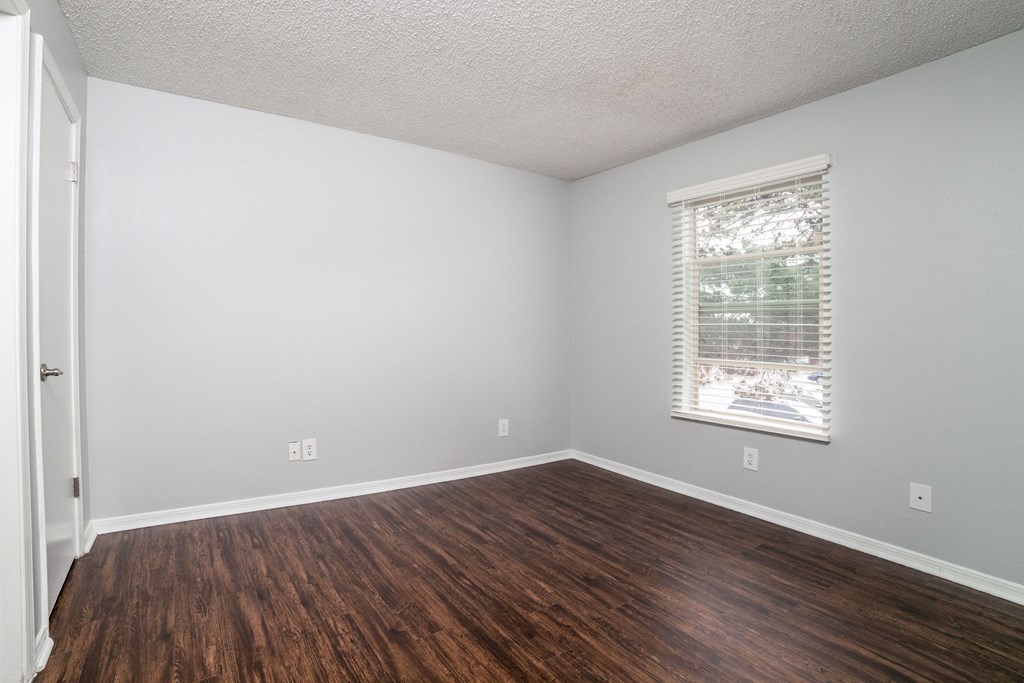 an empty living room with wood floors and a window