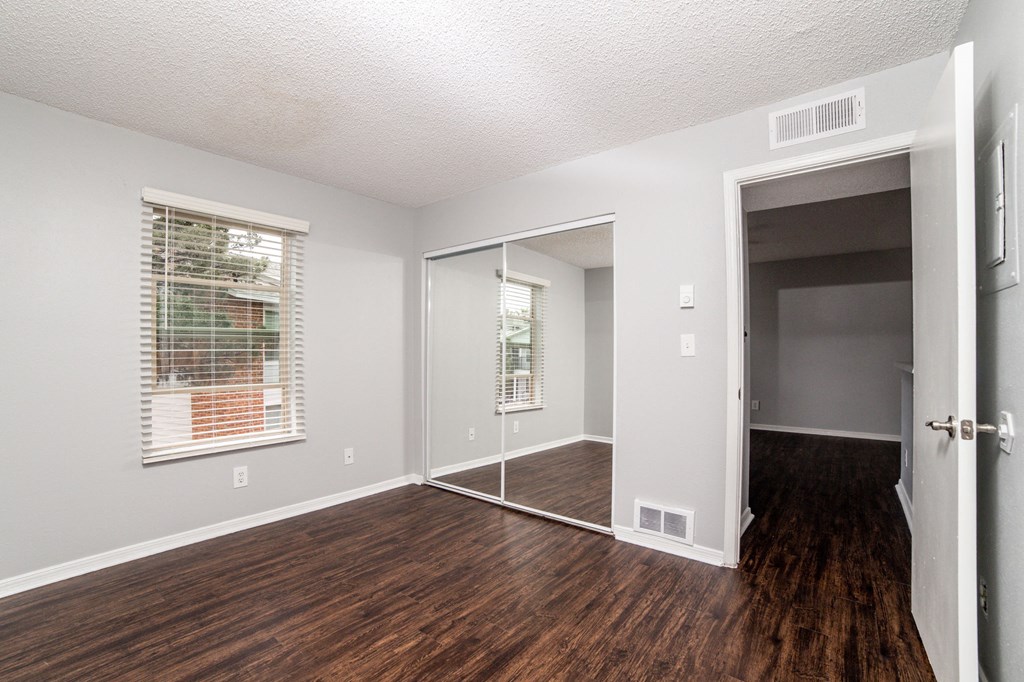 an empty living room with wood flooring and a door to a hallway