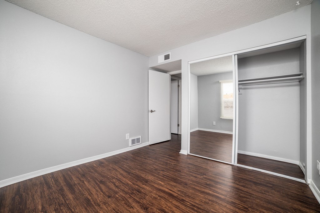 an empty living room with wood flooring and a door to a closet
