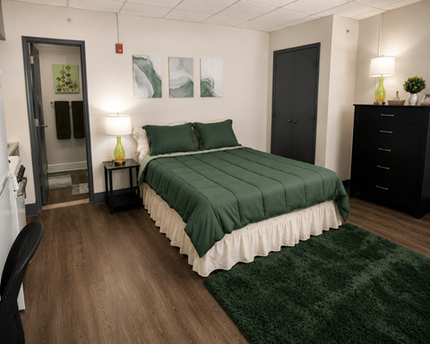 A bedroom with a bed, nightstand, and chair.