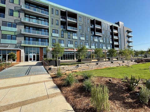 an exterior view of an apartment building with a sidewalk and grass