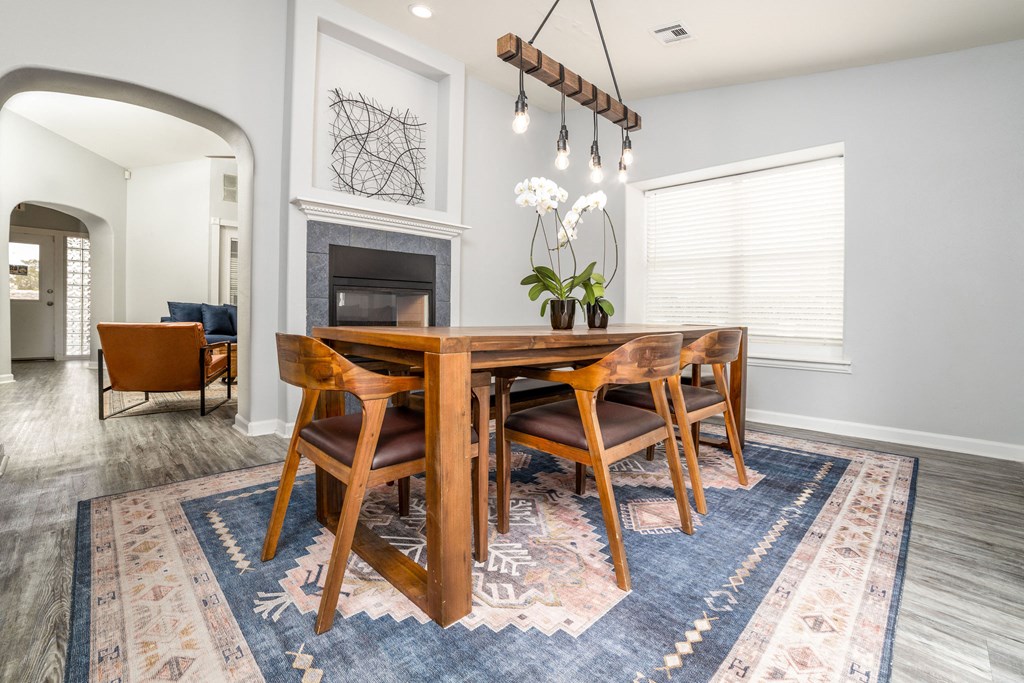 a dining room with a wooden table and chairs in front of a fireplace