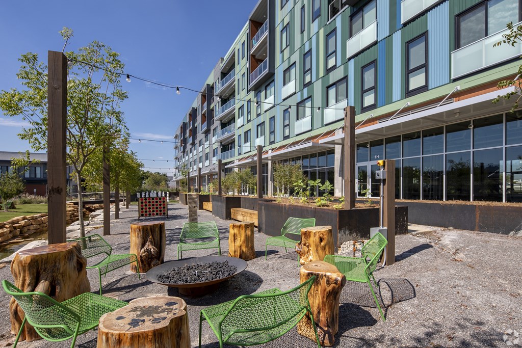 a courtyard with chairs and tables and a fire pit in front of a building