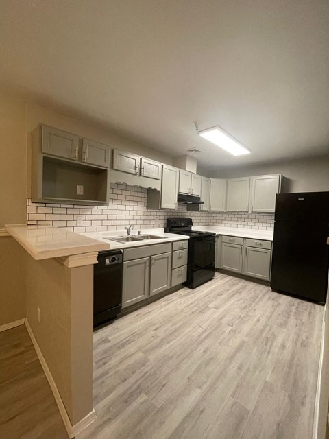 an empty kitchen with white cabinets and black appliances