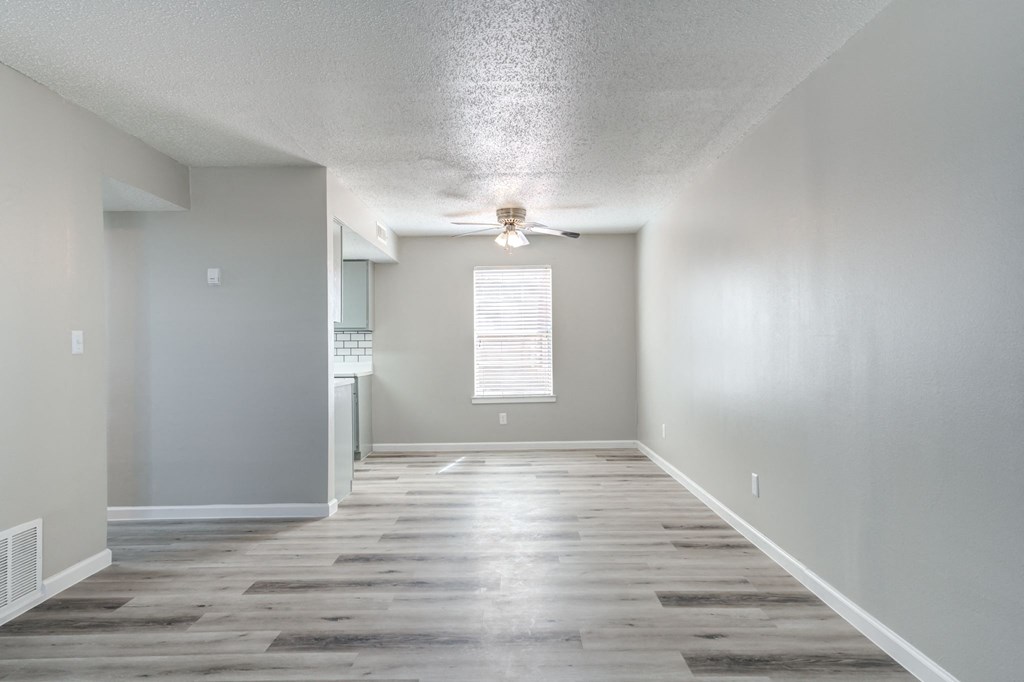 an empty living room with wood floors and a ceiling fan
