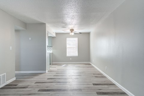 an empty living room with wood floors and a ceiling fan