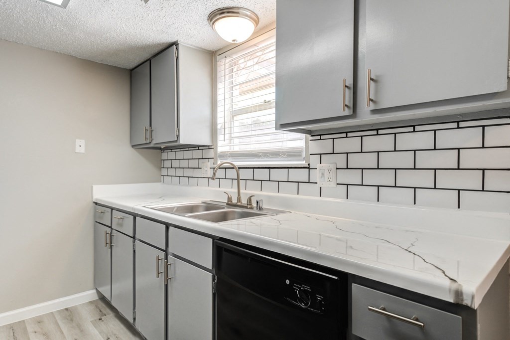 an empty kitchen with white quartz counter top and black dishwasher