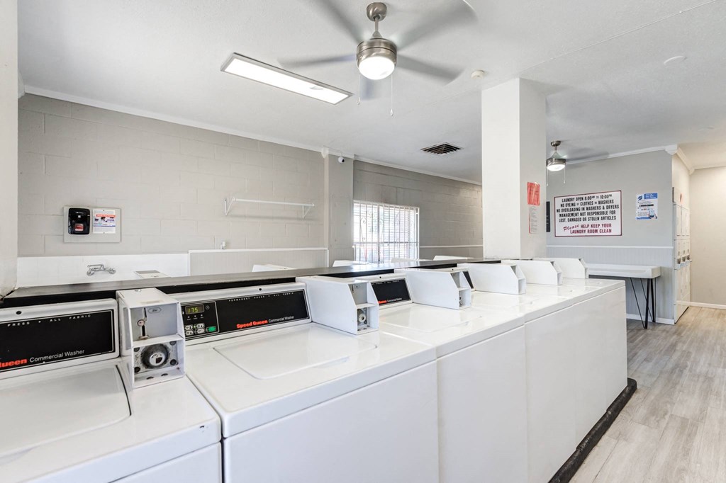 a group of washers and dryers in a room with microwaves