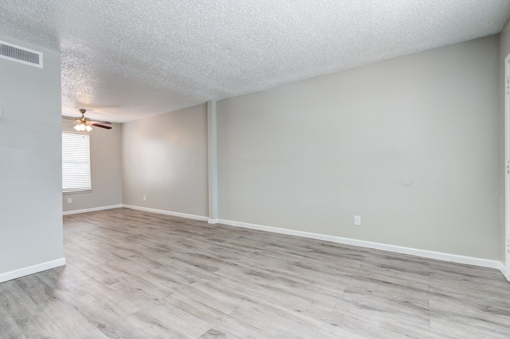 an empty living room with wood floors and a ceiling fan