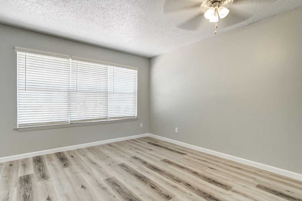 an empty bedroom with wood floors and a large window