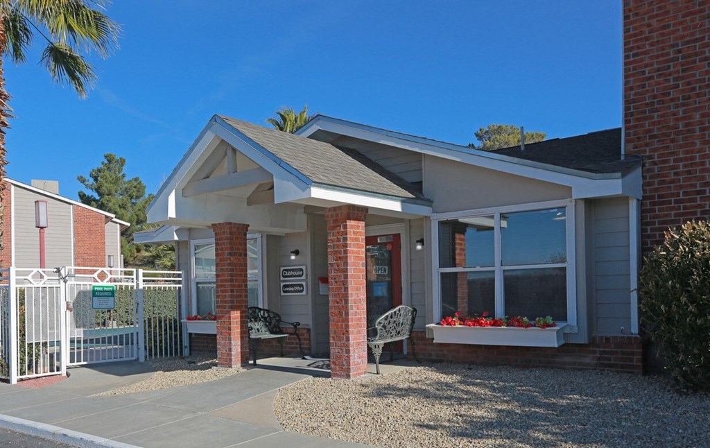 a small brick building with a porch and a white gate