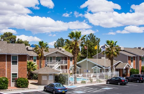 an apartment building with a pool and cars parked in a parking lot