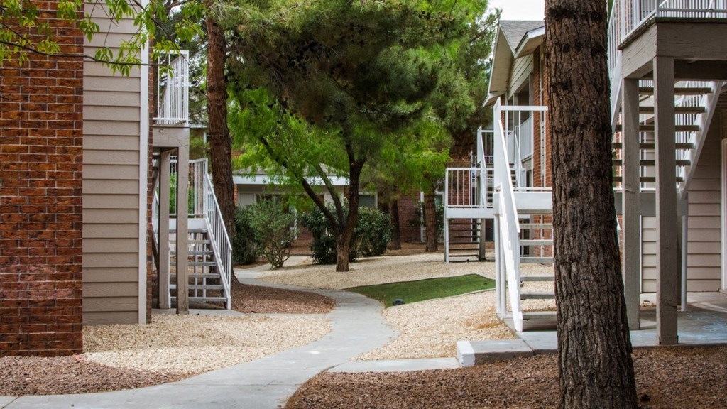 a path between buildings with trees and stairs